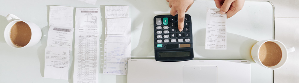 A table-scape shows someone working on their budget with receipts and a calculator.