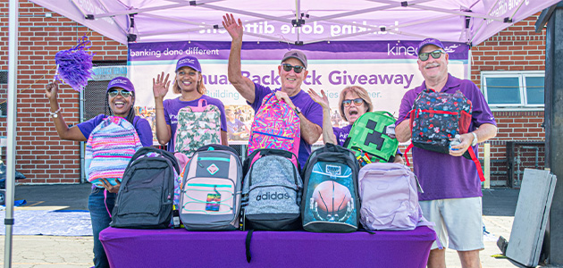 A group of Kinecta employees stand with filled backpacks during the drive.