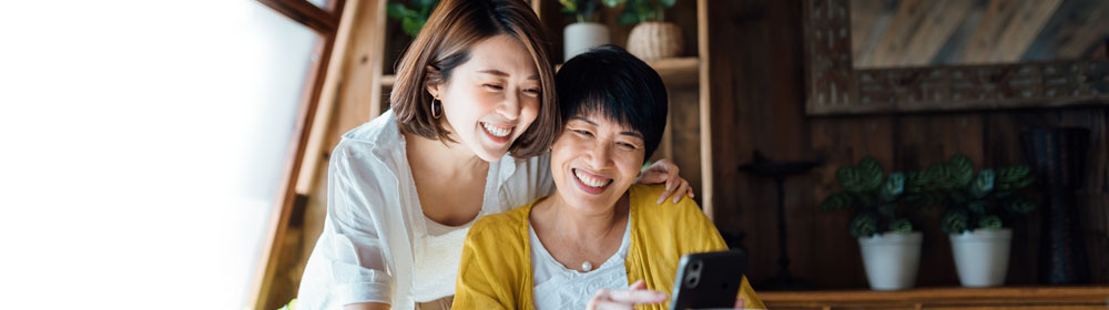 Two people looking at their mobile phone at the dinner table.